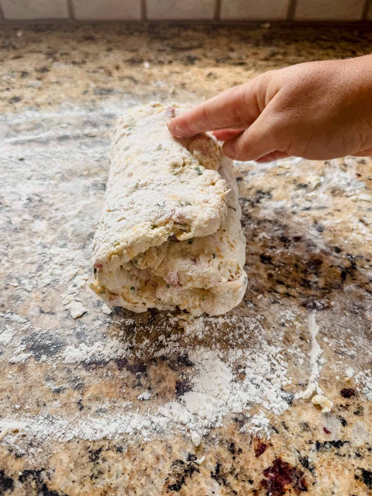 folding protein biscuit dough into a book fold on the counter.