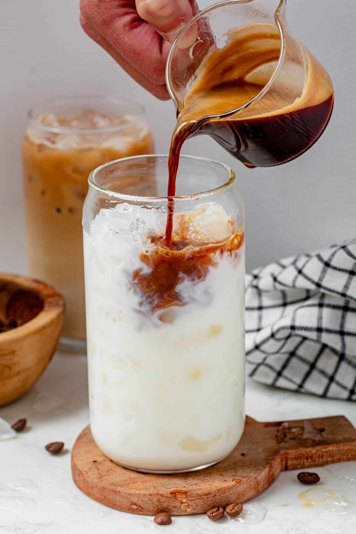 pouring a double shot of espresso into a vanilla protein shake with ice.