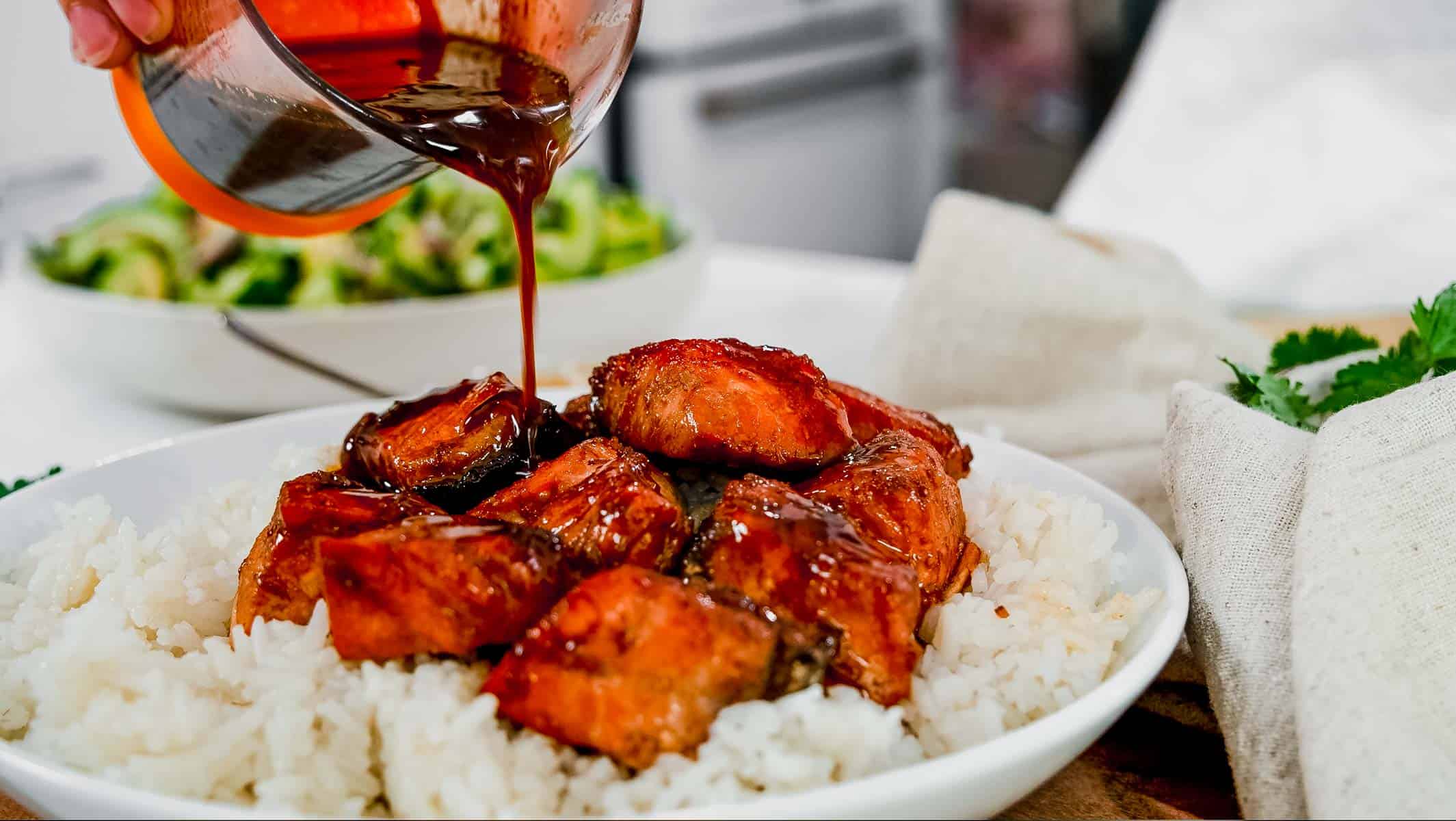 pouring sauce over salmon rice bowls