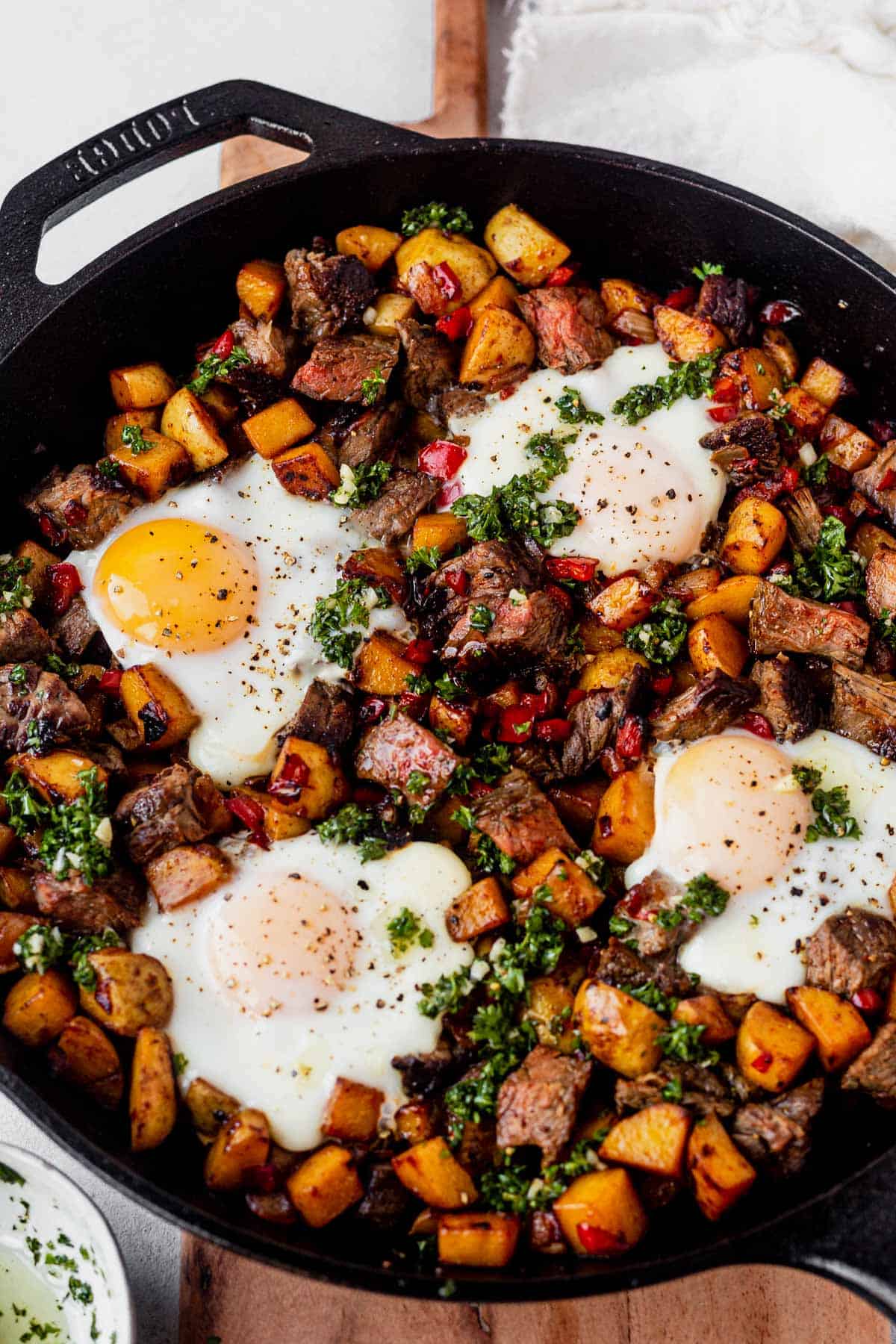 steak and potato breakfast hash in a cast iron skillet with fried eggs