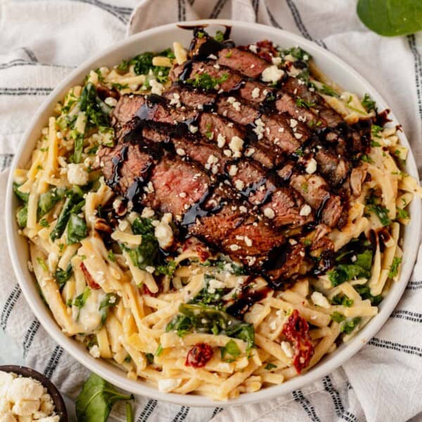 creamy balsamic steak pasta in a white bowl with gorgonzola
