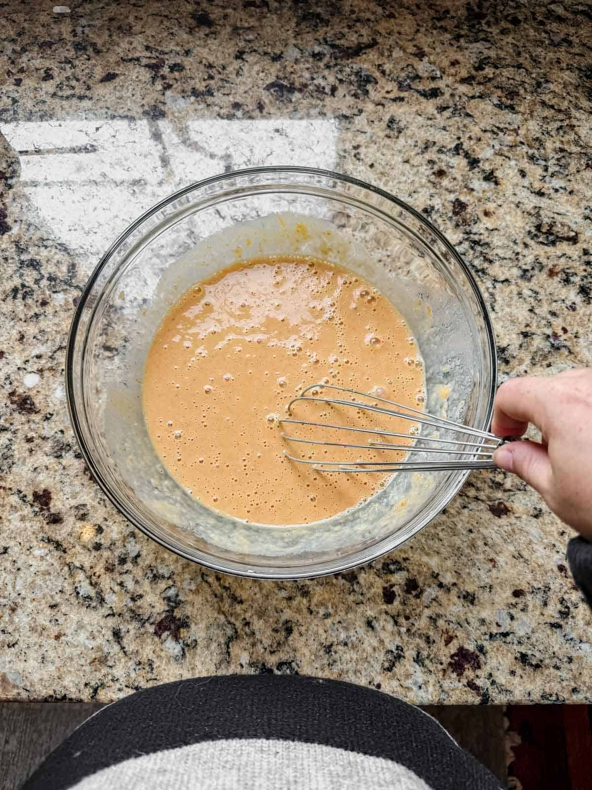 whisking pumpkin custard for french toast in a bowl.