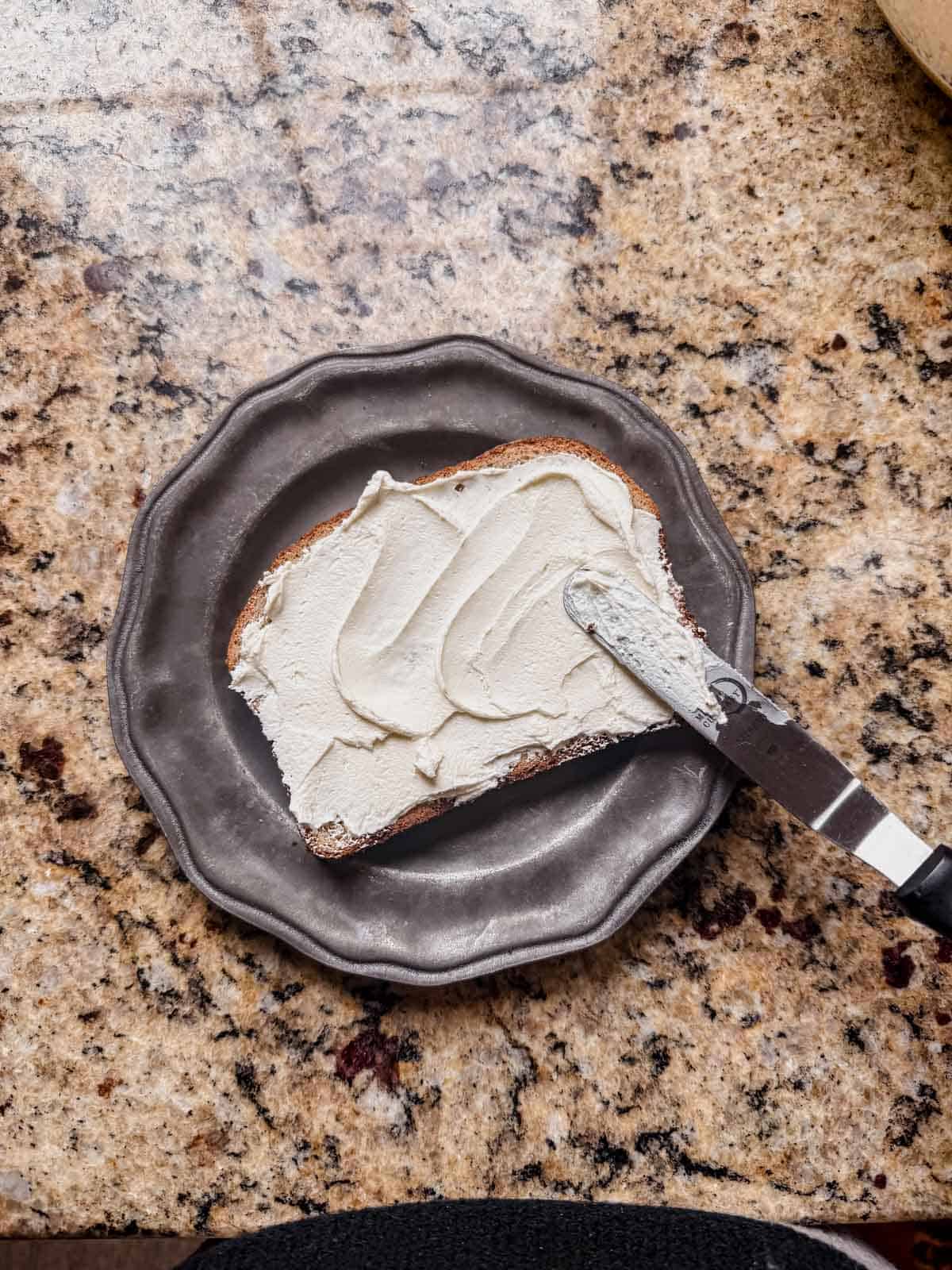 spreading cream cheese between two pieces of bread.