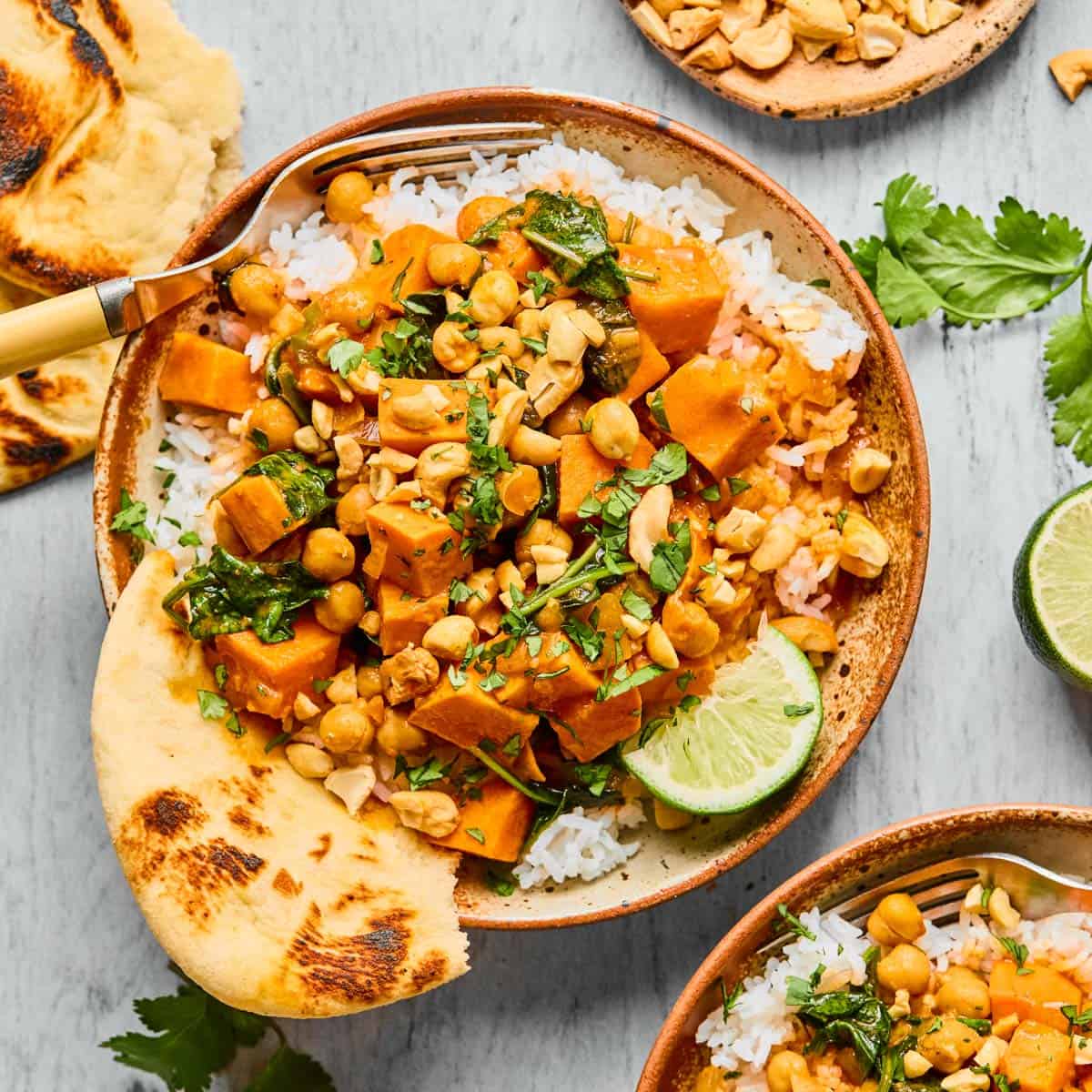 a bowl of sweet potato curry with rice and naan.