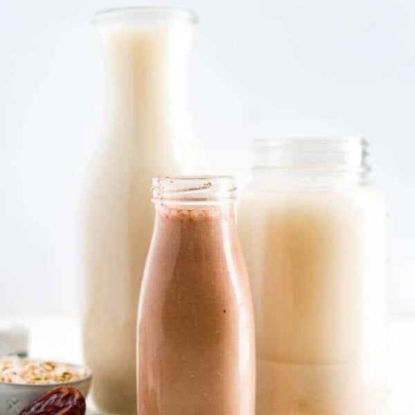 two glasses of homemade oat milk and one glass of chocolate oat milk