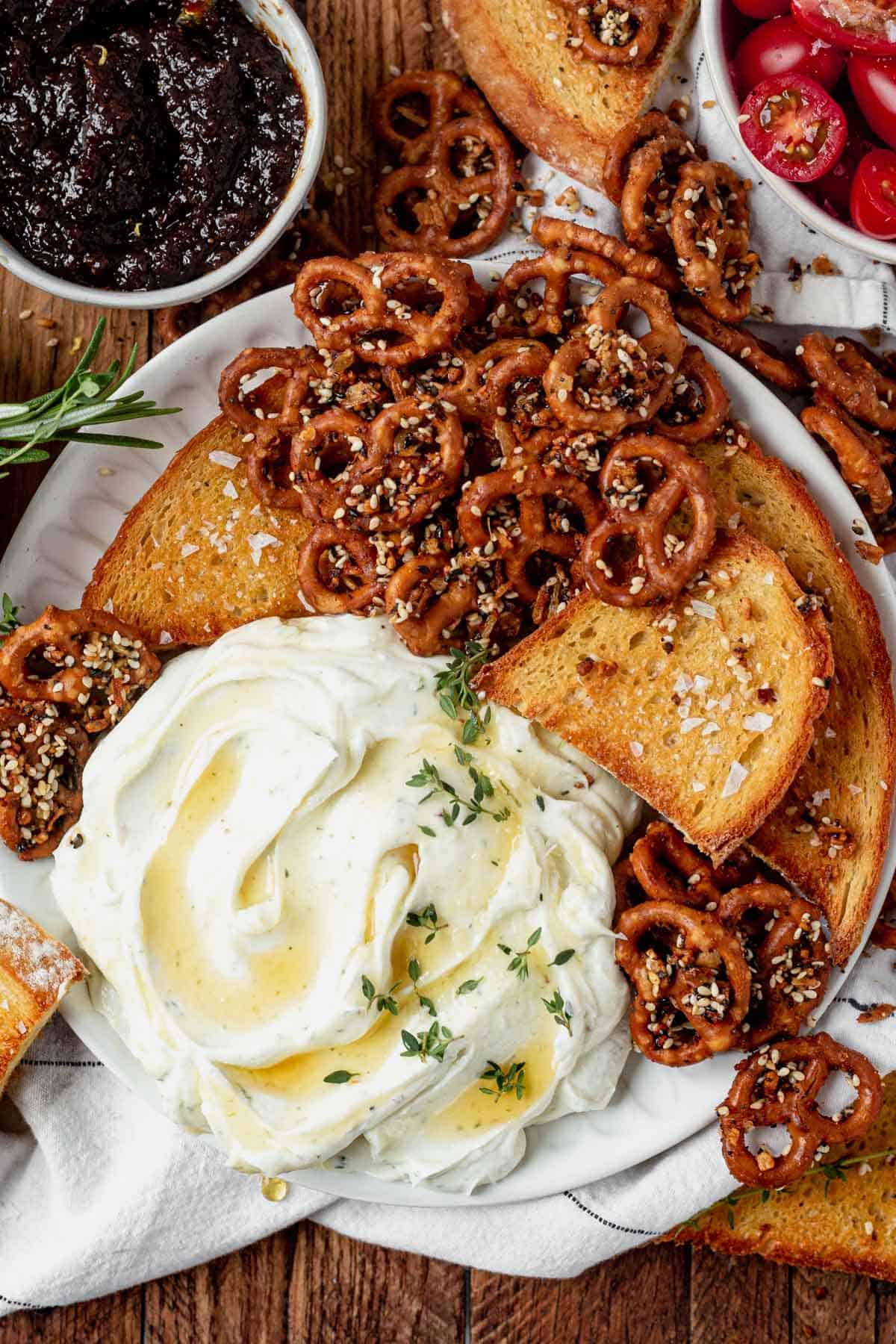 Easy creamy whipped goat cheese recipe with honey and herbs in a serving dish with bread and pretzels